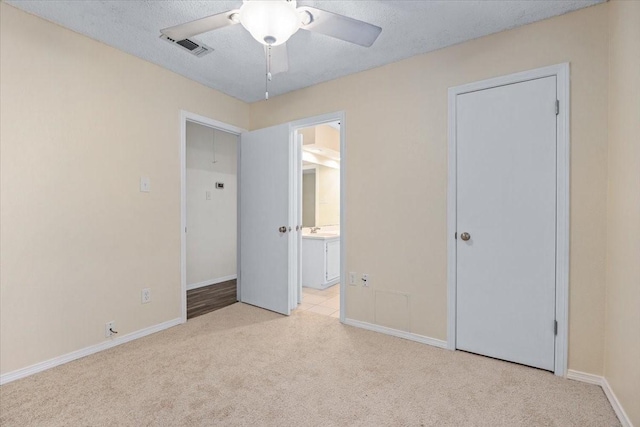 unfurnished bedroom with visible vents, ensuite bath, light carpet, and baseboards