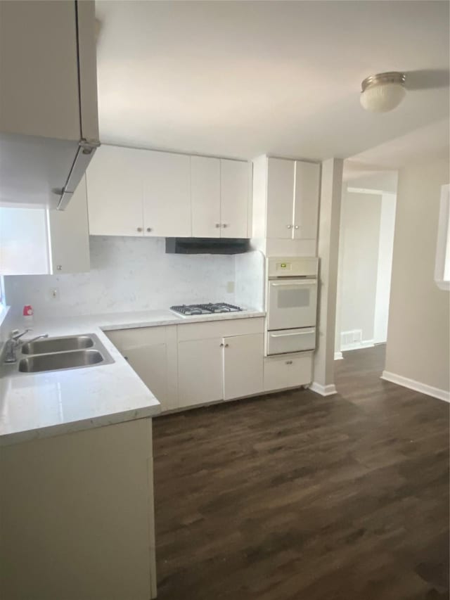 kitchen featuring white appliances, a warming drawer, light countertops, white cabinets, and a sink