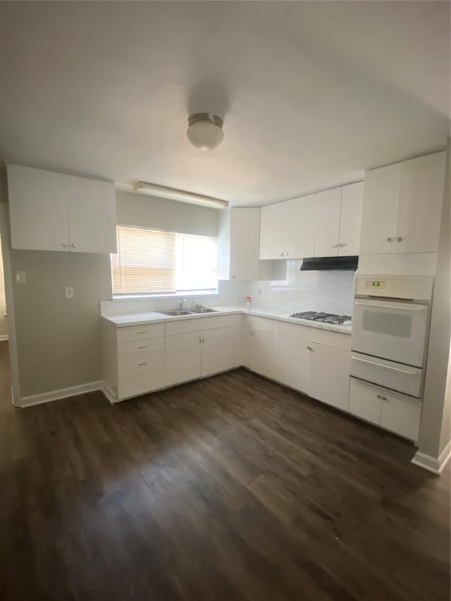 kitchen with a sink, oven, a warming drawer, light countertops, and white cabinets