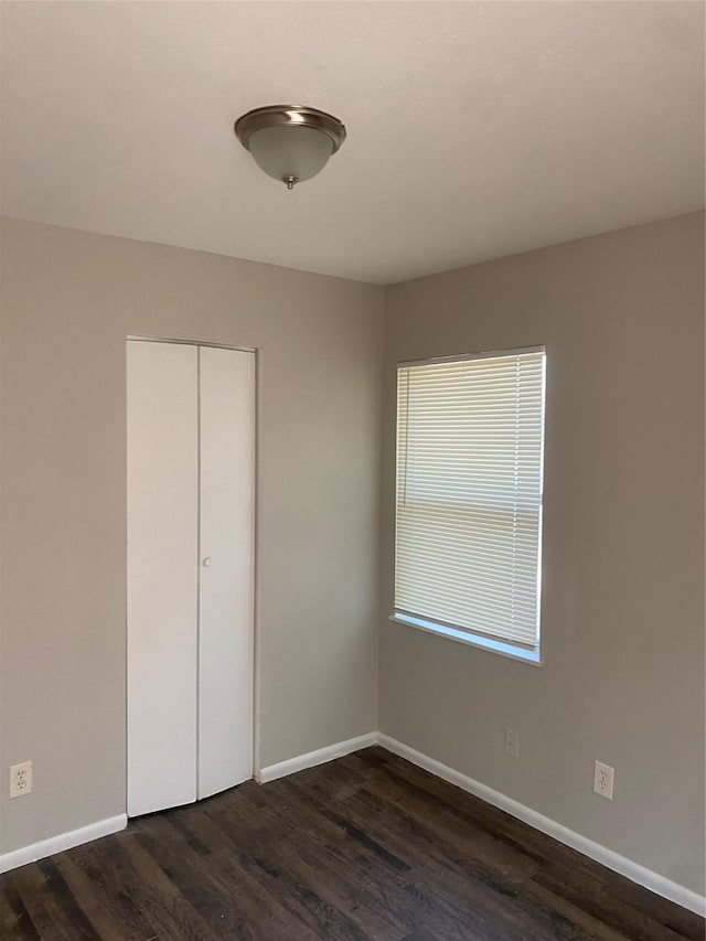 unfurnished bedroom with dark wood-style floors and baseboards
