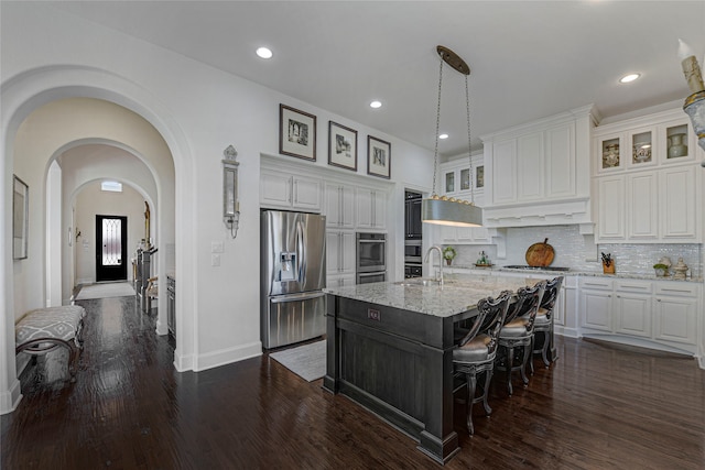 3429 Lochside, The Colony, TX 75056 - kitchen with white cabinets, light stone counters, stainless steel appliances, and an island with sink