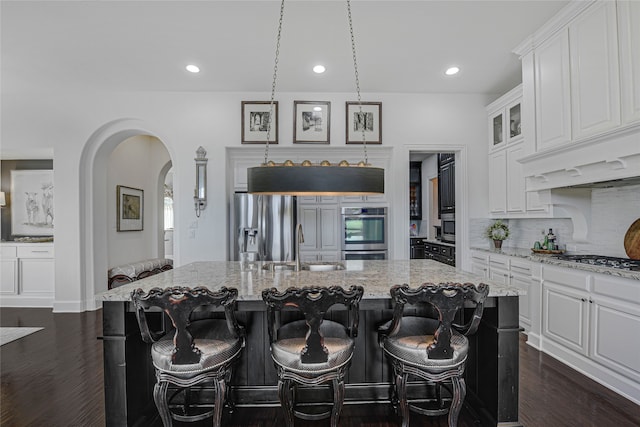 3429 Lochside, The Colony, TX 75056 - kitchen featuring tasteful backsplash, arched walkways, stainless steel appliances, white cabinetry, and dark wood-style floors