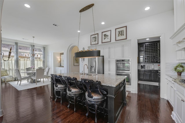 3429 Lochside, The Colony, TX 75056 - kitchen featuring double oven, light stone counters, a sink, visible vents, and dark wood-style floors
