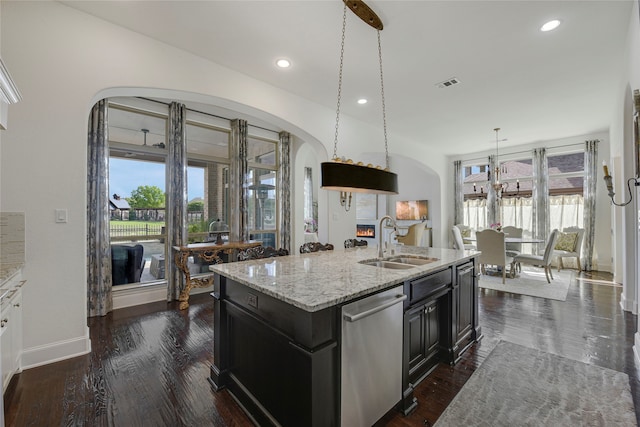 3429 Lochside, The Colony, TX 75056 - kitchen featuring light stone counters, stainless steel dishwasher, a sink, visible vents, and arched walkways