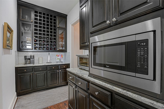 3429 Lochside, The Colony, TX 75056 - kitchen featuring light stone counters, glass insert cabinets, light wood finished floors, and stainless steel microwave