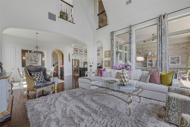 3429 Lochside, The Colony, TX 75056 - living room with arched walkways, wood finished floors, visible vents, a notable chandelier, and a towering ceiling