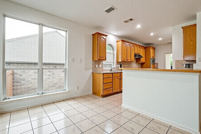 1415 Lowes Farm Pkwy, Mansfield, TX 76063 - kitchen featuring under cabinet range hood, tasteful backsplash, light countertops, light tile patterned flooring, and recessed lighting