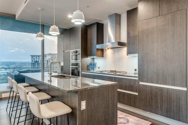 3130 N Harwood St Unit 901, Dallas, TX 75201 - kitchen with wall chimney range hood, dark wood-style flooring, appliances with stainless steel finishes, a sink, and modern cabinets