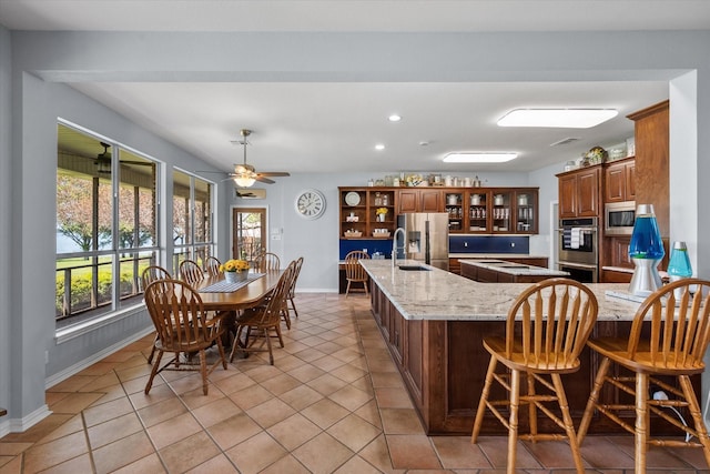 411 Pecan Point Dr, Kerens, TX 75144 - kitchen featuring a peninsula, light stone countertops, baseboards, brown cabinets, and stainless steel appliances