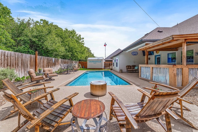 view of swimming pool with a patio, an outbuilding, a fenced in pool, a fenced backyard, and a shed