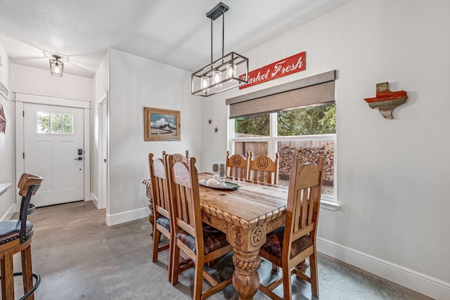 dining area featuring concrete floors, a chandelier, and baseboards