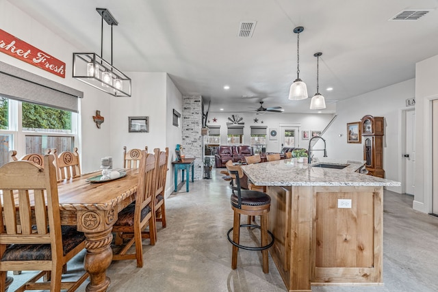 kitchen with a sink, a ceiling fan, visible vents, and concrete flooring