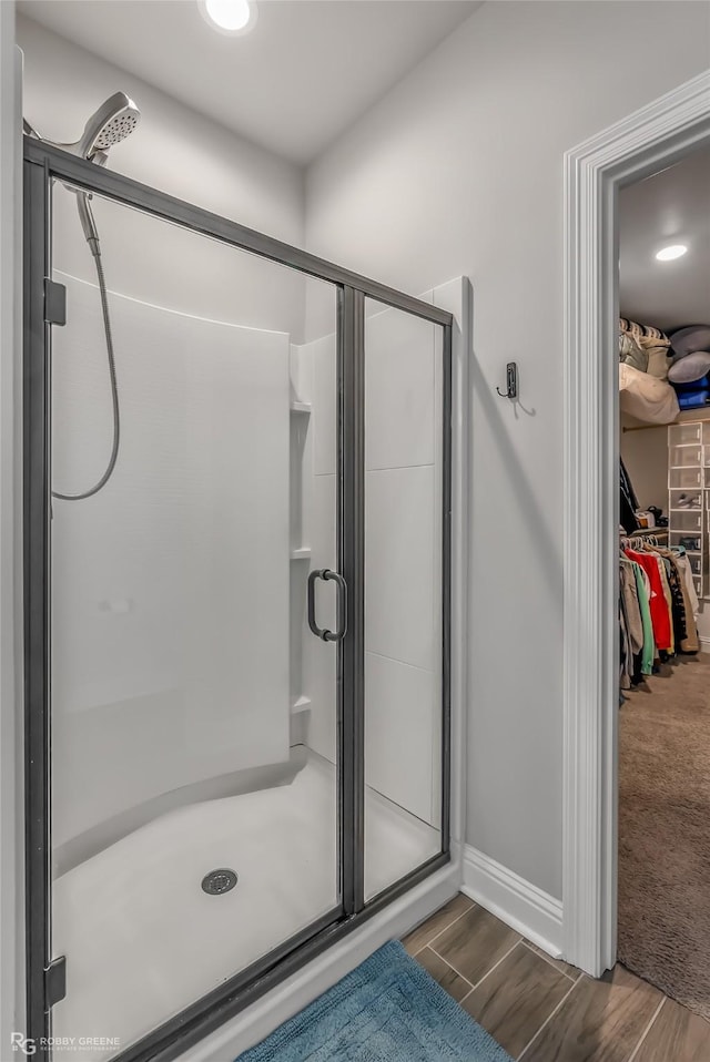 3843 Joseph Randall Dr, Shreveport, LA 71107 - full bathroom featuring wood finished floors, a walk in closet, a shower stall, and baseboards