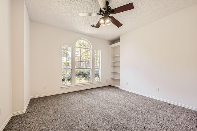 empty room with dark colored carpet, a textured ceiling, a ceiling fan, and baseboards