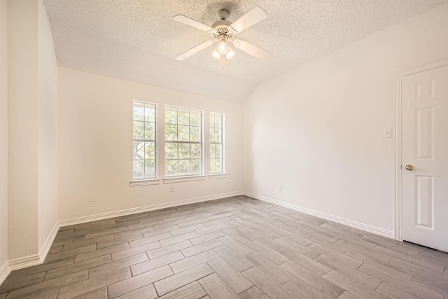 empty room with wood finished floors, ceiling fan, baseboards, a textured ceiling, and lofted ceiling