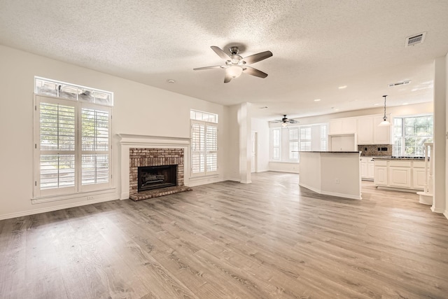 unfurnished living room featuring a ceiling fan, a wealth of natural light, and a textured ceiling