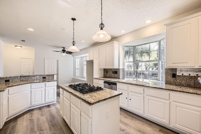 kitchen with a textured ceiling, a sink, stainless steel appliances, and light wood-style floors