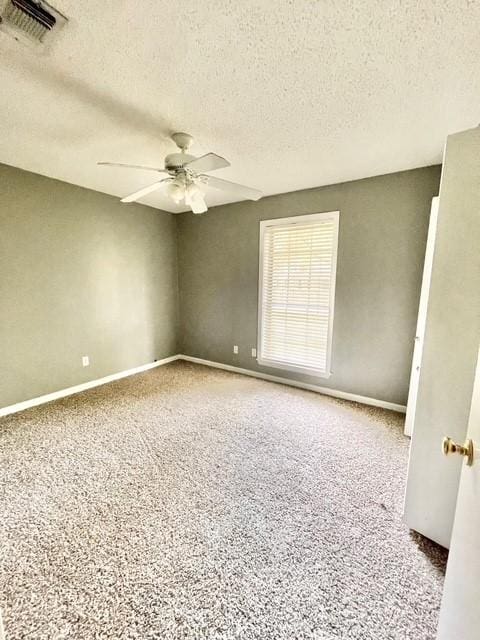 unfurnished room featuring baseboards, visible vents, a ceiling fan, and a textured ceiling