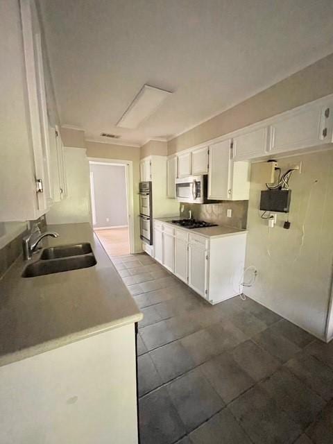 kitchen featuring a sink, stainless steel appliances, tasteful backsplash, visible vents, and white cabinetry