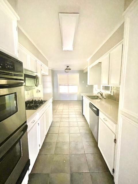 kitchen featuring a sink, tile patterned floors, light countertops, white cabinets, and appliances with stainless steel finishes
