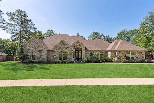 french provincial home featuring french doors, a front lawn, and stone siding