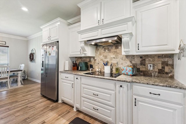 kitchen with white cabinetry, decorative backsplash, black electric stovetop, light wood-type flooring, and stainless steel fridge