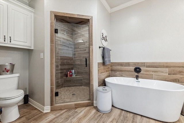 full bath featuring crown molding, a stall shower, toilet, wood finished floors, and a freestanding bath