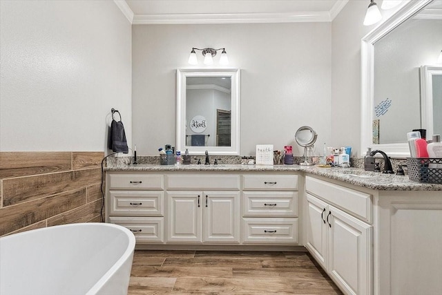 bathroom with crown molding, double vanity, a sink, and a freestanding tub