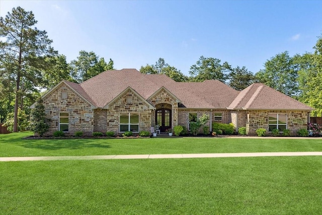 view of front of home featuring a front lawn, stone siding, and french doors