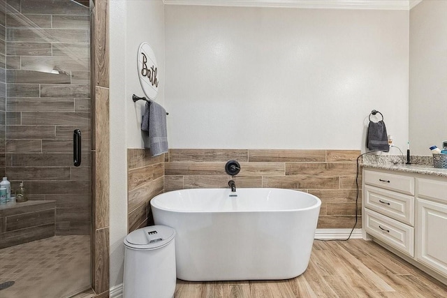 full bathroom with a shower stall, vanity, a soaking tub, wainscoting, and wood finished floors