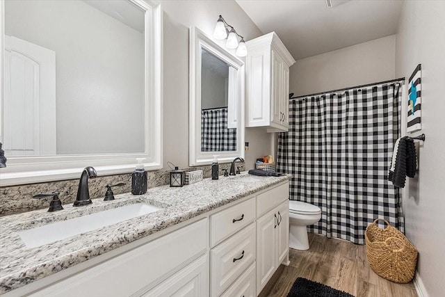full bath featuring wood finished floors, toilet, double vanity, and a sink