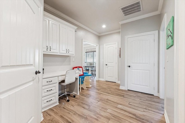 home office featuring visible vents, ornamental molding, light wood-type flooring, and built in desk