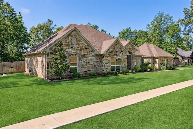 view of front facade with fence, a front lawn, and stone siding