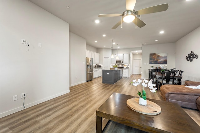 living room featuring baseboards, recessed lighting, ceiling fan, and light wood-style floors