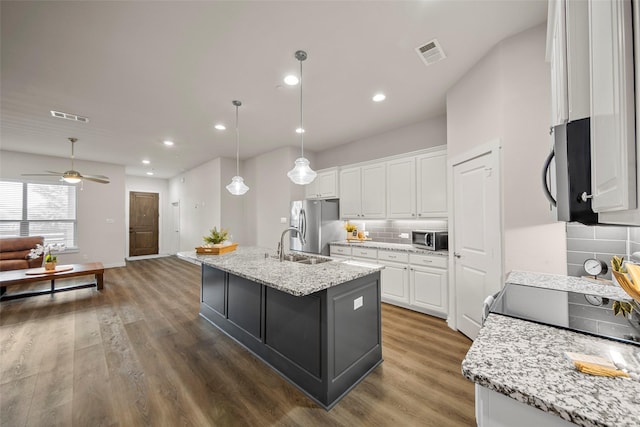 kitchen with open floor plan, visible vents, stainless steel appliances, and backsplash