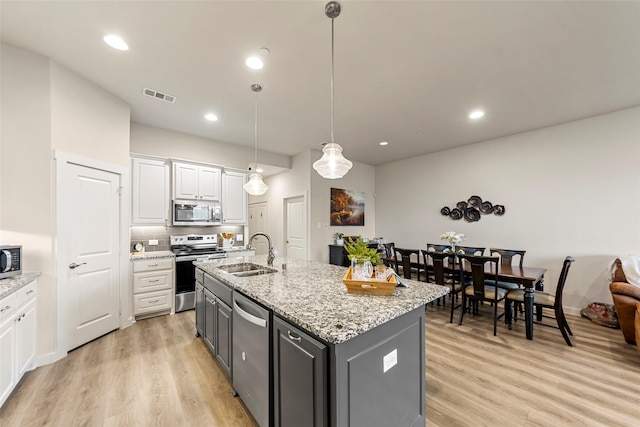 kitchen featuring light wood-style flooring, white cabinets, a sink, visible vents, and stainless steel appliances