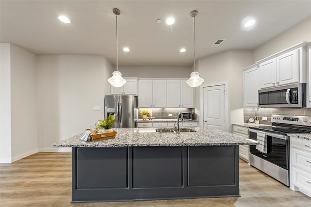 kitchen with a sink, white cabinets, appliances with stainless steel finishes, and tasteful backsplash