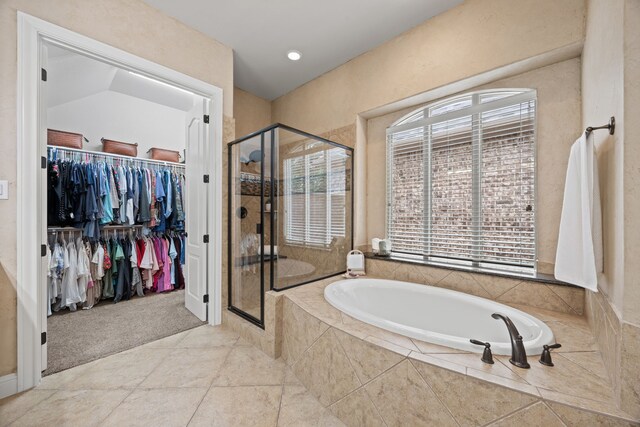 full bathroom with a wealth of natural light, a shower stall, a bath, and a walk in closet