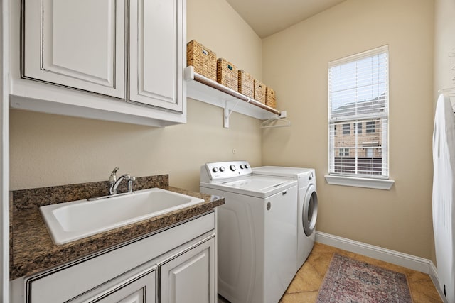 washroom with a sink, cabinet space, light tile patterned flooring, baseboards, and washer and dryer