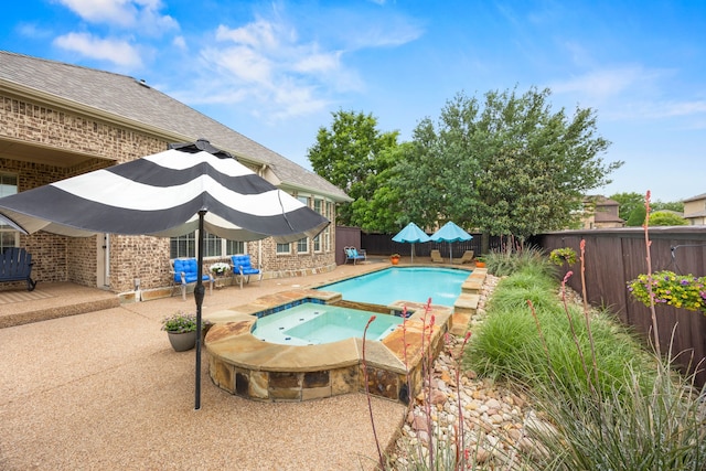view of swimming pool featuring a pool with connected hot tub, a patio, and a fenced backyard
