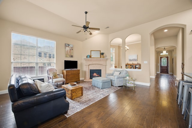 living area featuring dark wood-style flooring, ceiling fan, visible vents, and arched walkways