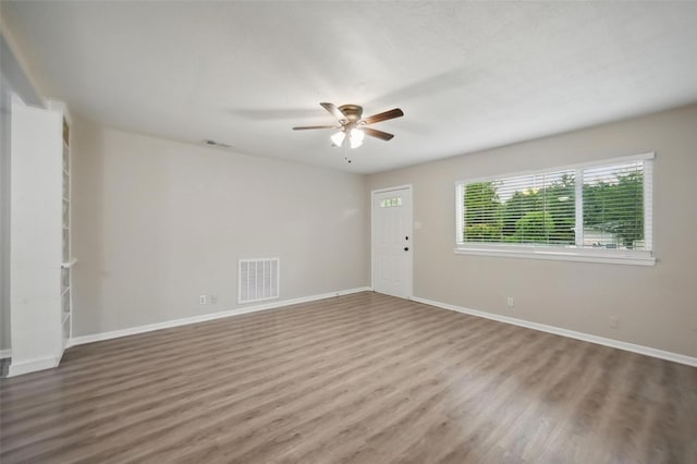 unfurnished room with baseboards, visible vents, wood finished floors, and a ceiling fan