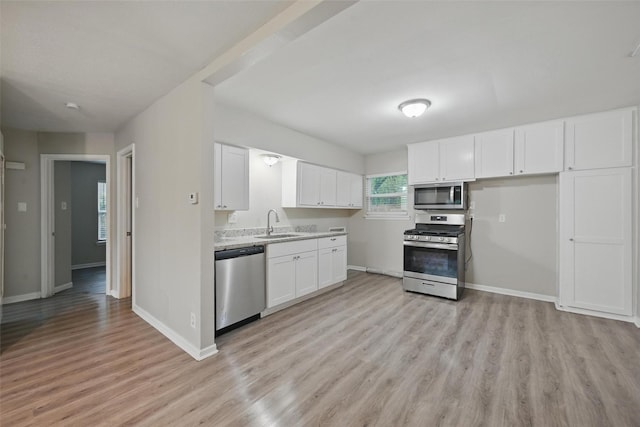 kitchen featuring baseboards, stainless steel appliances, light wood-style floors, and a sink
