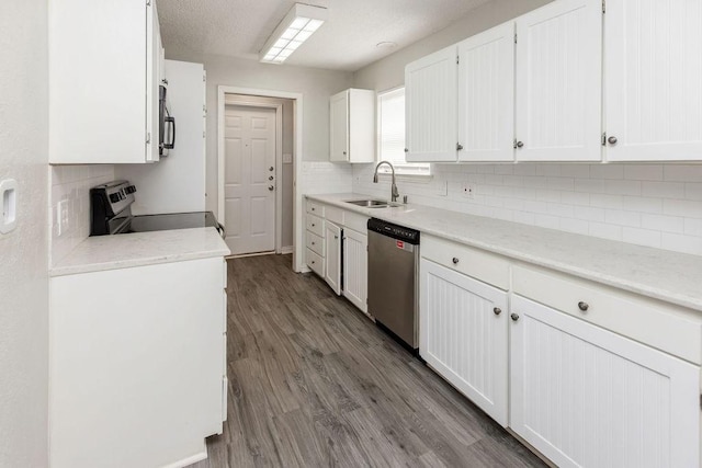kitchen with white cabinetry, decorative backsplash, a sink, stainless steel appliances, and light countertops