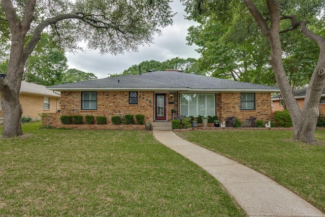 single story home featuring brick siding, a shingled roof, and a front yard