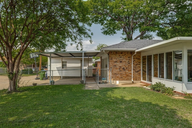 back of property featuring fence, a gate, and a yard
