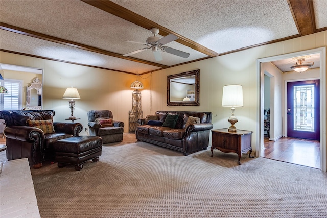 carpeted living room featuring a ceiling fan, a textured ceiling, crown molding, and beamed ceiling