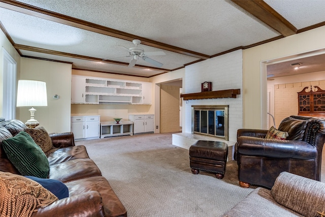 living area with a textured ceiling, beamed ceiling, a brick fireplace, carpet, and a ceiling fan