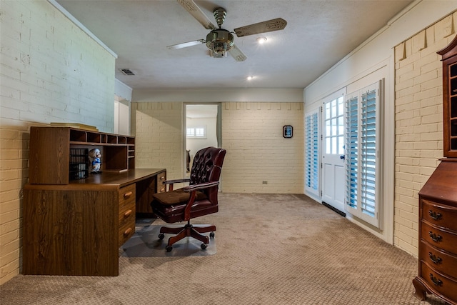 office with visible vents, ceiling fan, carpet floors, and brick wall