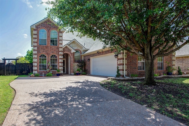 traditional-style house featuring driveway, an attached garage, fence, and brick siding